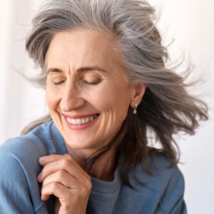 Mulher de cabelos grisalhos sorrindo com tranquilidade, ilustrando a reabilitação com prótese protocolo na Mooca