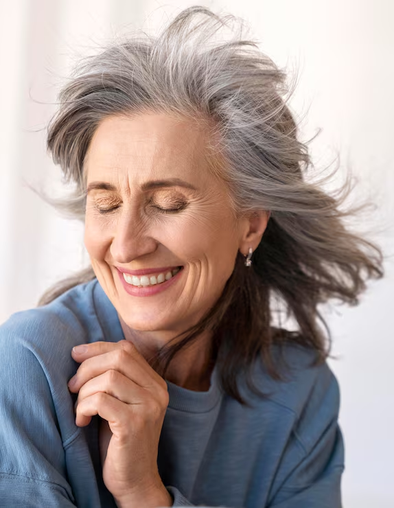 Mulher de cabelos grisalhos sorrindo com tranquilidade, ilustrando a reabilitação com prótese protocolo na Mooca